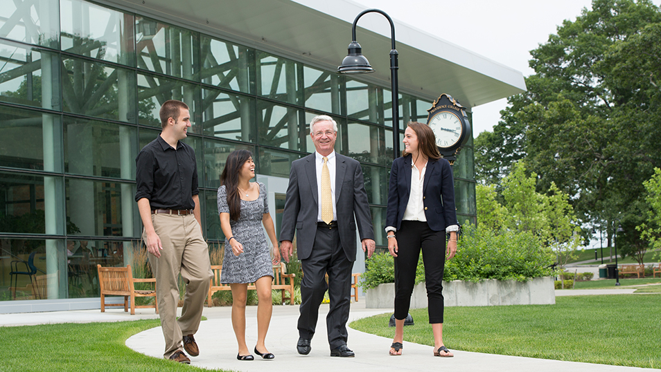Students and businessman walking on campus